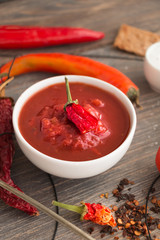Chili sauce, salsa sauce, dried chili pods, fresh chili pods on wooden table. Selective focus.