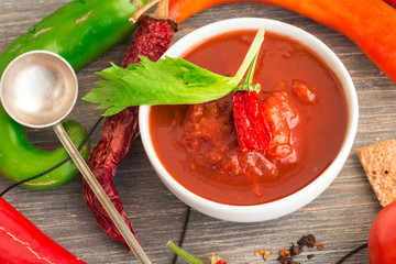 Chili sause, salsa sauce, dried chili pods, fresh chili pods, salt, dried chili spice, rye bread crisp, salt, tomatoes on wooden table. Cooking concept.