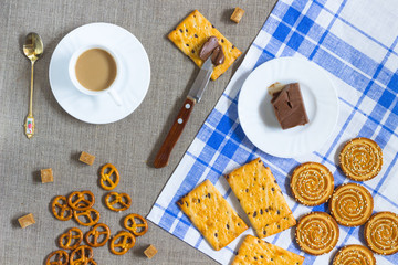 Cookies, cup of coffee, peanut butter, and a knife. top view
