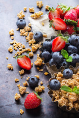 Homemade muesli granola in bowl with berries on rusty table
