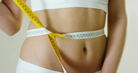  beautiful young woman measures the perfect body with a tape measure to understand the effects of diet and weight loss healthy diet and nutrition concept
