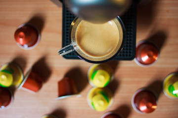 una tazza di caffe fragrante di mattina, che ha fatta con macchina del caffe. Su sfondo sono capsule colorati