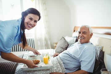 Nurse serving breakfast to senior man