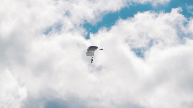 Military parachutists lands on a background of clouds and blue sky