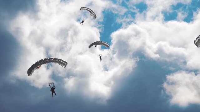 Military parachutists lands on a background of clouds and blue sky