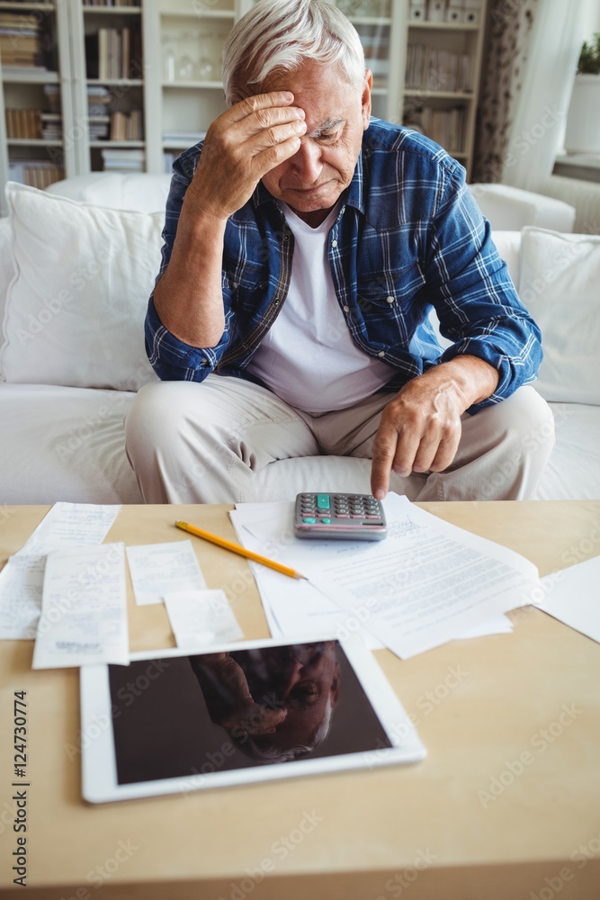 Wall mural Tensed senior man checking the bills