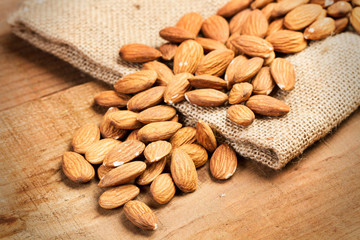 Almendras sobre tabla de madera rústica y saco de arpillera. Vista superior