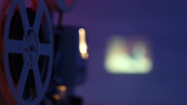 Retro film projector projecting a movie on the wall with red-blue light