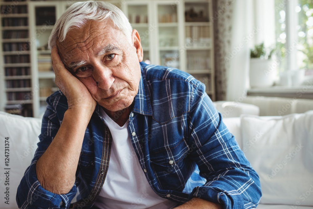 Wall mural portrait of worried senior man sitting on a sofa