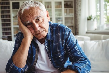 Portrait of worried senior man sitting on a sofa