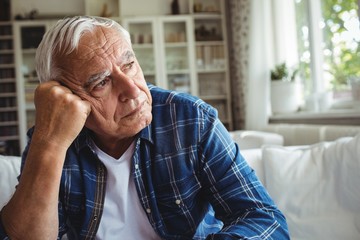 Worried senior man sitting on a sofa - obrazy, fototapety, plakaty