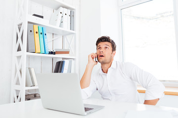 Businessman talking on mobile phone while sitting at office desk
