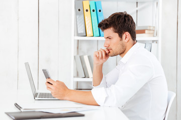 Young businessman in white shirt working with laptop and smartphone