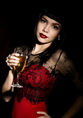 Fototapeta na wymiar Young celebrating woman in a red dress holding a glass of champagne