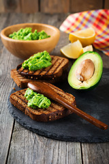 Sandwiches with guacamole traditional Mexican sauce, avocado and lemon on old wooden background. Selective focus.