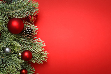 Fototapeta na wymiar Weihnachten / Tannenzweig auf rotem Hintergrund