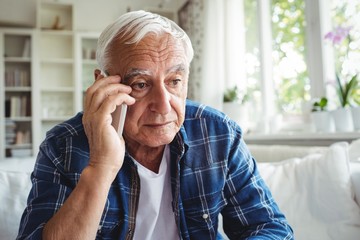 Tensed senior man talking on mobile phone