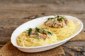 Tasty pasta with mushrooms, cheese and dill on a plate on old wooden background. Vegetarian pasta nests with the stuffing recipe. Closeup