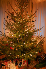 Christmas tree with beautiful decorations, fairy lights and presents underneath