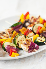 Closeup of chicken skewers or shashlik with grilled vegetables (mushrooms, paprika, salad, zucchini, onion).