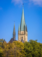 Fototapeta na wymiar Herz-Jesu-Kirche mit Herbstwald und blauem Himmel - Paderborn, Deutschland.