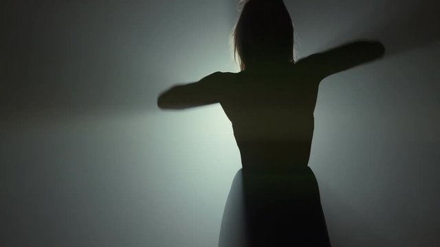 Silhouette of ballerina dancing in studio lights
