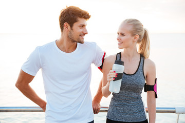 Beautiful young cheerful couple talking while resting after workout