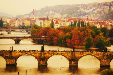 Naklejka premium Center of Prague city at autumn with red roofs and Charles Bridge over river Vltava, european travel landscape background in vintage style