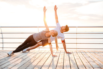 Fototapeta na wymiar Smiling couple doing yoga exercises outdoors