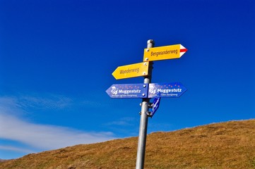 Wegweiser am Wanderweg in den Schweizer Bergen vor blauem Himmel