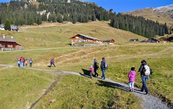 Wandergruppe auf der M&auml;gisalp, Berner Oberland in den Schweizer Bergen - mit Alph&uuml;tten im Hintergrund
