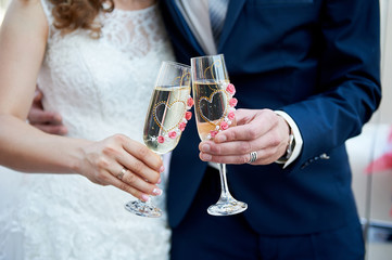 bride and groom are holding two glasses of champagne