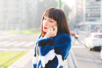 Half length of young beautiful eastern woman walking outdoor in city back light, talking smart phone, overlooking - technology, communication, work concept