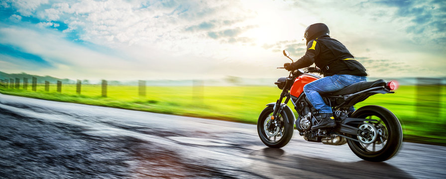 Motorrad f&auml;hrt auf freier Landstrasse in den Sonnenuntergang