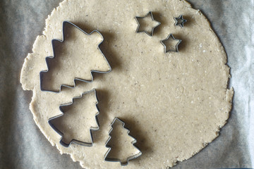 Christmas cookie cutters on the raw dough on the parchment top view