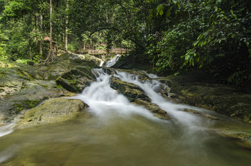 beautiful in nature, amazing cascading tropical waterfall. wet and mossy rock, surrounded by green rain forest