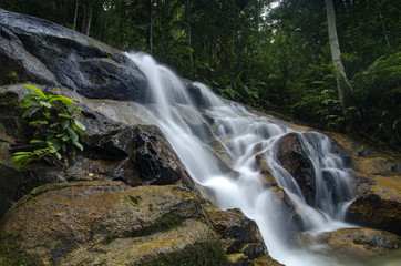 beautiful in nature, amazing cascading tropical waterfall. wet and mossy rock, surrounded by green rain forest