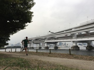 Man running on park path with Rainbow Bridge in background