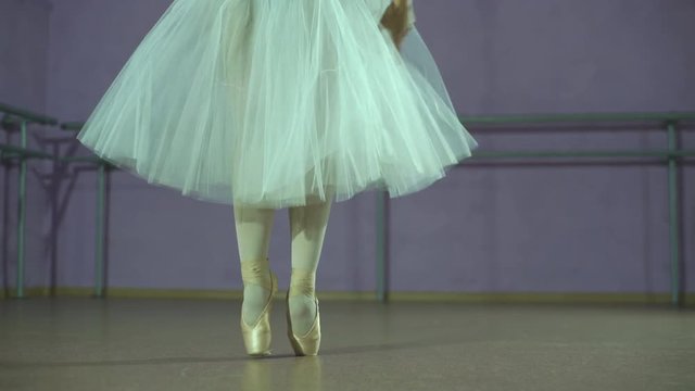 Closeup of dancing legs of ballerina wearing white pointes