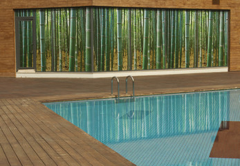 Swimming pool with old wooden flooring and blue water and bamboo