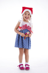 Girl in santa hat. in full growth in polka-dot dress with a toy owl in the hands of the playful toddler