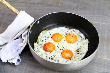 A pan with four fried eggs and a worn out cotton napkin.