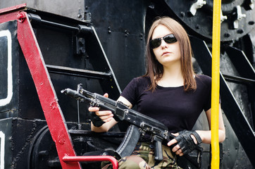 Girl with a gun sitting on the running board of a steam locomotive