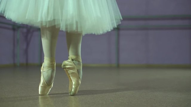 Closeup of dancing legs of ballerina wearing white pointes