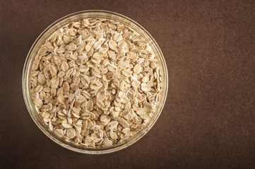 Food. Oatmeal on the table. Dry rolled oat flakes oatmeal in brown bowl on old wooden table.