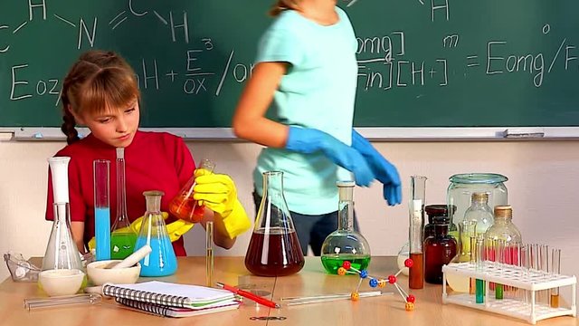 Children looks into flask in chemistry class. Kids spend chemical experiments, ending explosion. Children are taught chemistry.