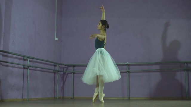 ballerina making a jump in a dance hall. She is wearing the leotard with white tutu
