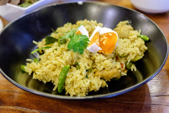 Rice yellow green curry with boiled egg in black dish