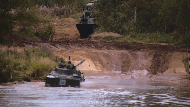 Armored military BMP and soldiers on the board, successful cross the river by swimming. Quadrocopter shooting 