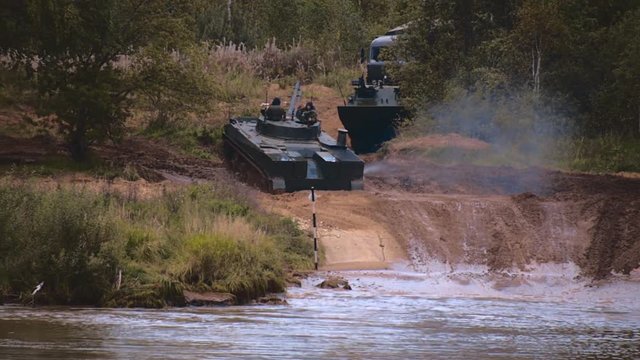Armored military BMP and soldiers on the board, successful cross the river by swimming. Quadrocopter shooting 